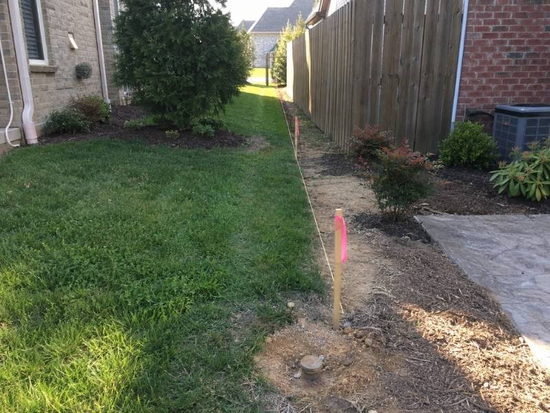 Property line surveying in Bowling Green KY showing marked boundary points between neighboring residential properties.